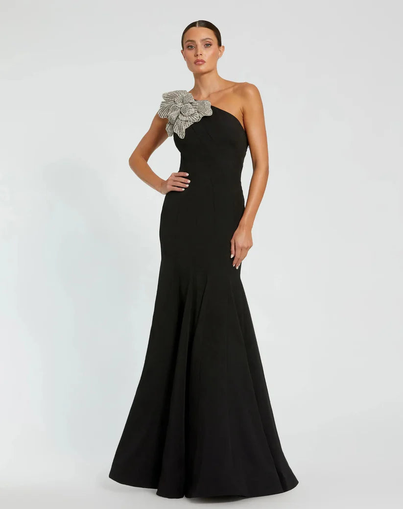 Model wearing Mac Duggal 11810 one-shoulder trumpet gown with flower detail.  Model wearing the dress in the color black.  Front view.