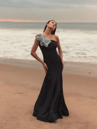 Model wearing Mac Duggal 11810 one-shoulder trumpet gown with flower detail.  Model wearing the dress in the color black. 