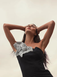 Model wearing Mac Duggal 11810 one-shoulder trumpet gown with flower detail.  Model wearing the dress in the color black. 