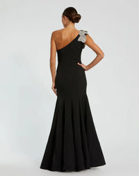 Model wearing Mac Duggal 11810 one-shoulder trumpet gown with flower detail.  Model wearing the dress in the color black.  Back view.