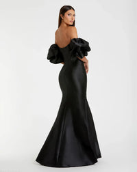 Model wearing Mac Duggal 50677 off-the-shoulder satin gown with puff sleeves, mermaid silhouette, and sweeping train.  Model is wearing the color black. Back view.