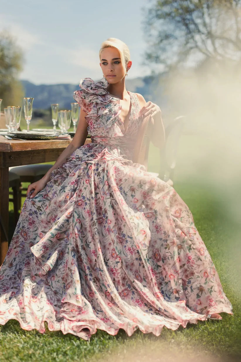 Model wearing Mac Duggal 68947 floral chiffon ballgown with plunging V-neckline, ruffle shoulder detail, and voluminous A-line skirt.  Model is wearing the dress in pinkMulti.  Front view.  Model is outside.