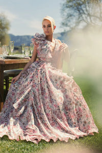 Model wearing Mac Duggal 68947 floral chiffon ballgown with plunging V-neckline, ruffle shoulder detail, and voluminous A-line skirt.  Model is wearing the dress in pinkMulti.  Front view.  Model is outside.