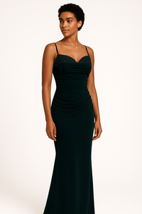 Model wearing the Madeline’s Bella gown with beaded bodice, spaghetti straps, and ruched fitted skirt in navy and emerald green.