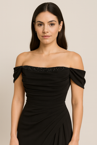 Model wearing Madeline’s Catherine off-shoulder beaded gown with ruched bodice and floor-length skirt.  The model is wearing the color Black.  Close up Front view.