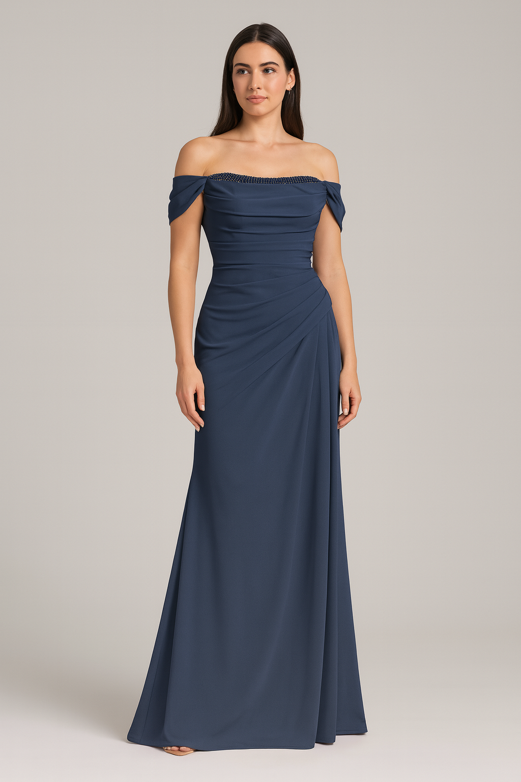 Model wearing Madeline’s Catherine off-shoulder beaded gown with ruched bodice and floor-length skirt.  The model is wearing the color Navy.  Front view.