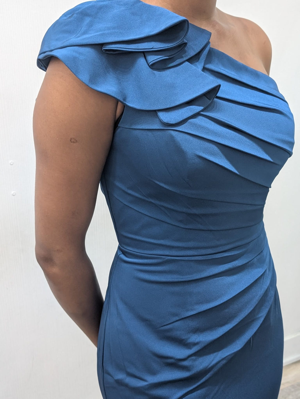 Model wearing the Madeline’s Chloe one-shoulder floor-length gown with ruched detailing and a statement ruffle shoulder.