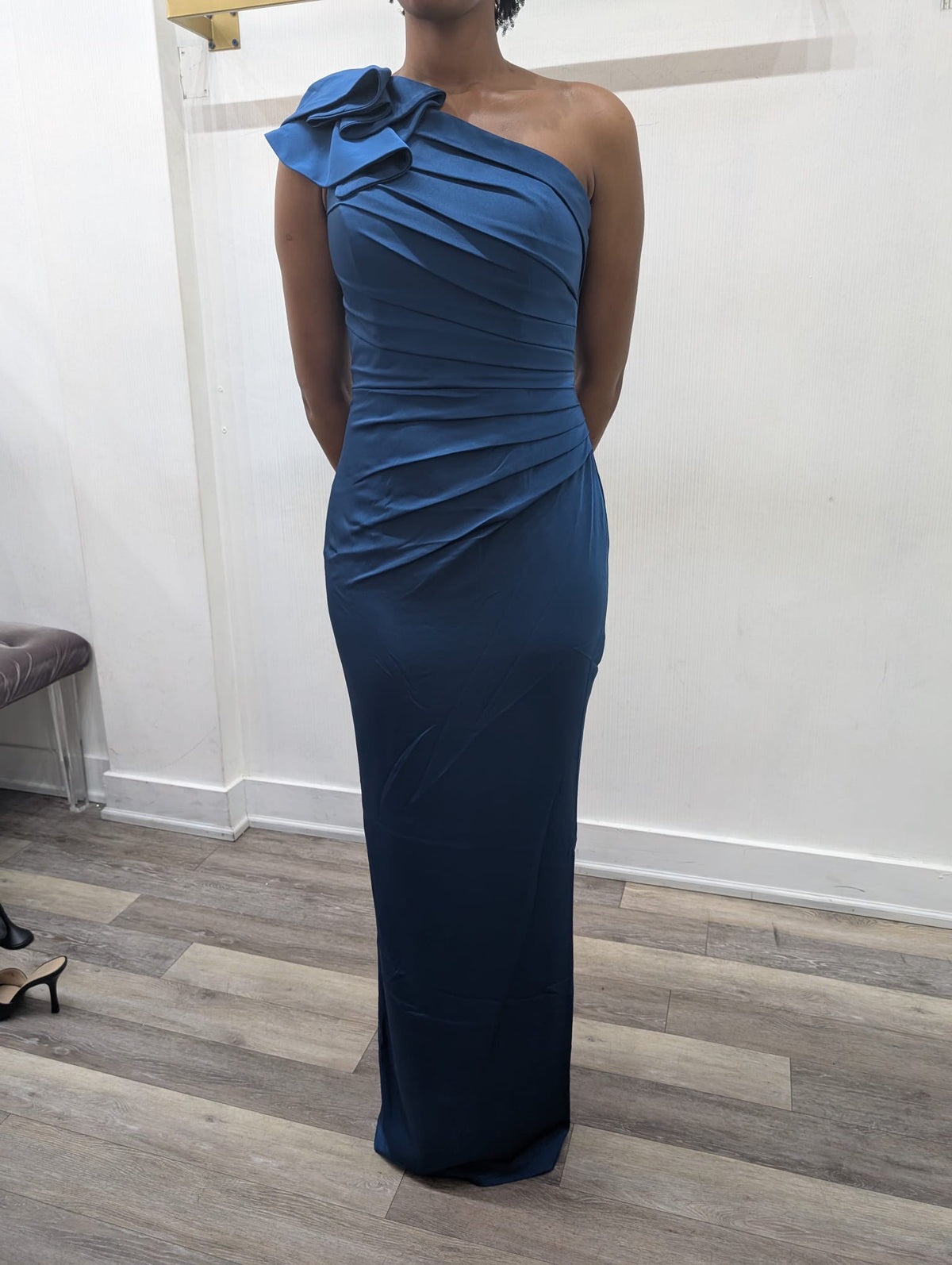 Model wearing the Madeline’s Chloe one-shoulder floor-length gown with ruched detailing and a statement ruffle shoulder.