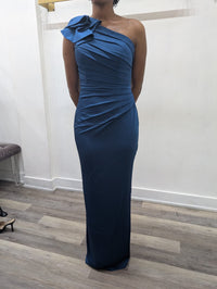 Model wearing the Madeline’s Chloe one-shoulder floor-length gown with ruched detailing and a statement ruffle shoulder.