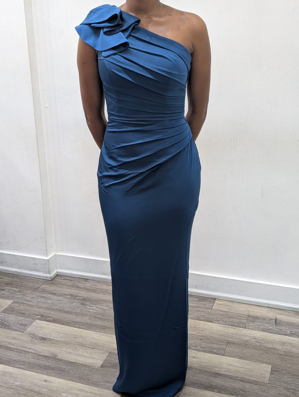 Model wearing the Madeline’s Chloe one-shoulder floor-length gown with ruched detailing and a statement ruffle shoulder.