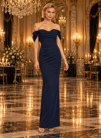 A woman modeling a floor-length off-the-shoulder navy blue gown in an elegant, opulent ballroom with gold chandeliers and marble floors.