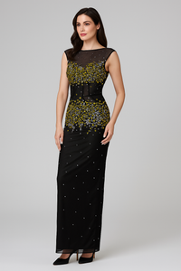 Woman wearing a black evening gown with green embellishments on a gray background