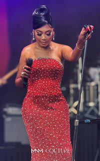Woman in a red dress with 'MNM Couture' on stage holding a microphone.