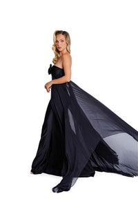 Model wearing Nicole Bakti 7388 gown featuring a strapless bow bodice and chiffon overlay