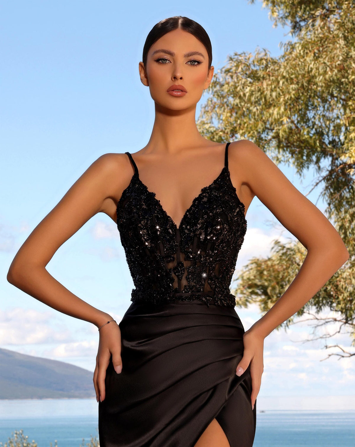 Model wearing Nicoletta NC2032 gown with a beaded bodice, draped slit skirt, and lace-up back.