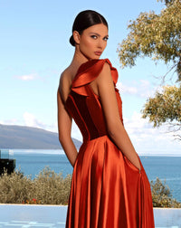 Model wearing Nicoletta NC2062 one-shoulder satin gown with ruffled shoulder and high slit in black, cadet blue, emerald, and vermillion.
