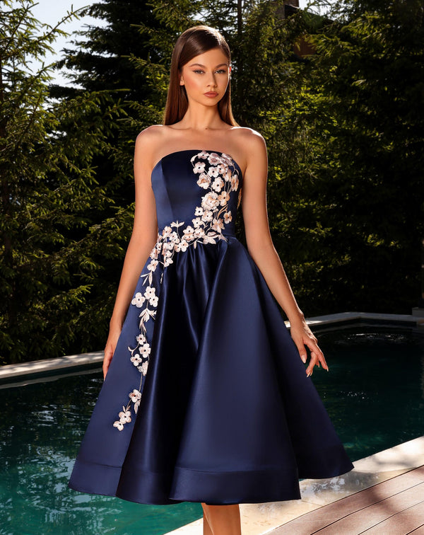 Model wearing Nicoletta NC2079 strapless navy and black A-line dress with floral appliqué and full midi skirt.