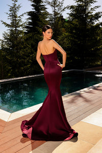 Model wearing Nicoletta NC2080 strapless black gown with blush floral embroidery in a mermaid silhouette by a pool.  Model is wearing the dress in the color burgundy.