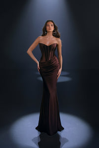 Woman wearing a dark brown strapless gown against a black background