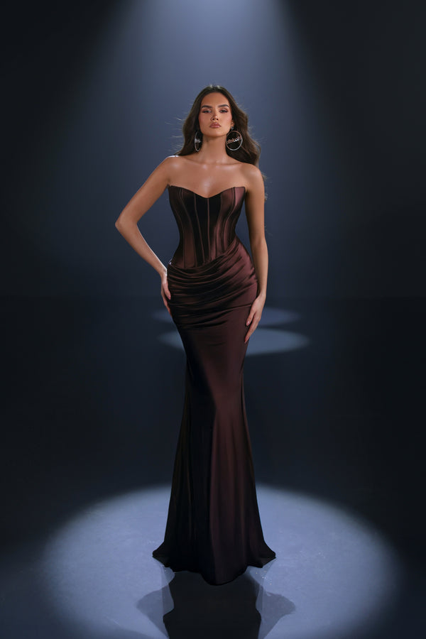 Woman wearing a dark brown strapless gown against a black background