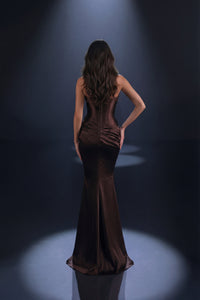Woman in a brown evening gown standing in spotlight on a dark background