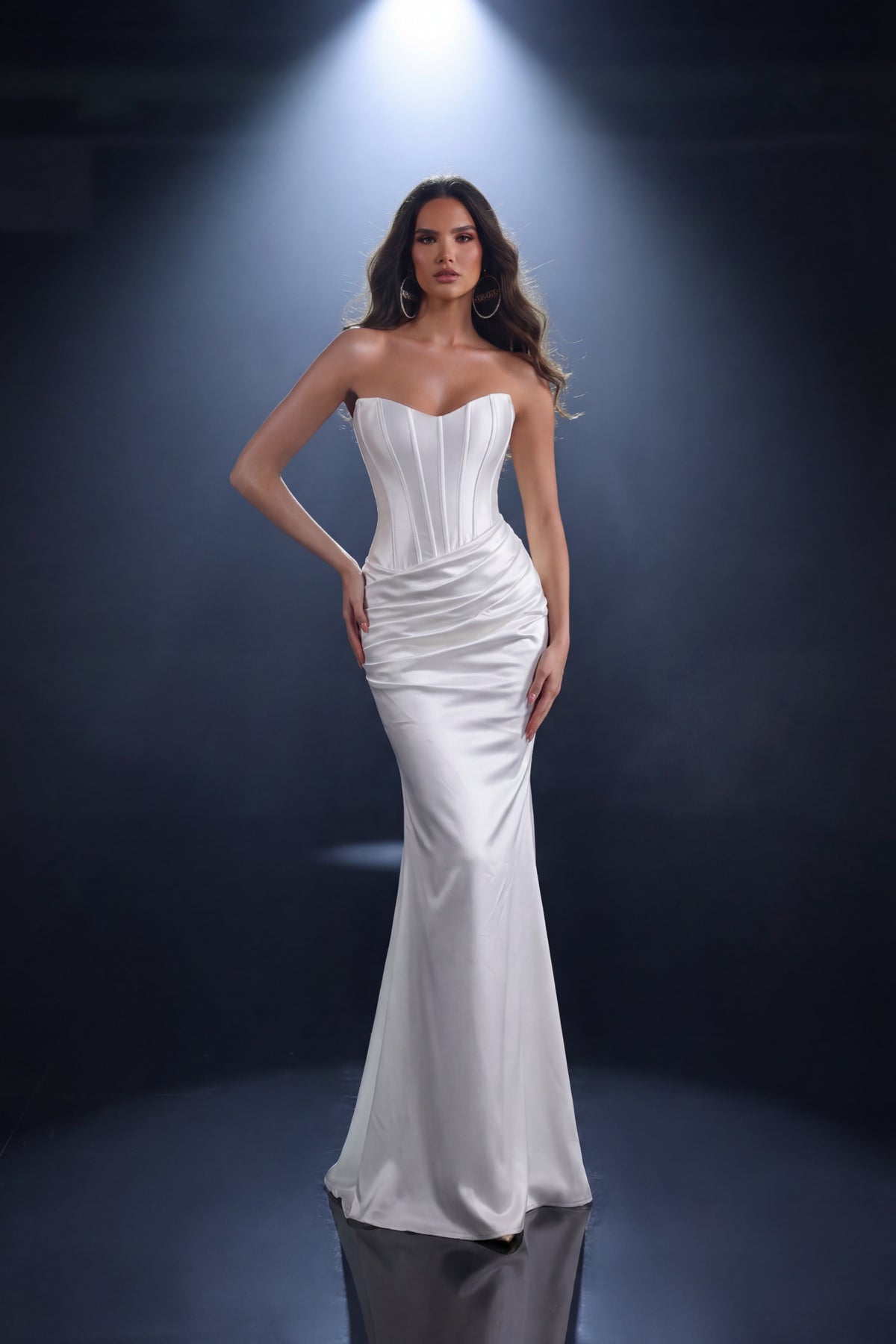 Woman wearing a ivory strapless gown against a dark background