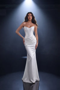 Woman wearing a ivory strapless gown against a dark background
