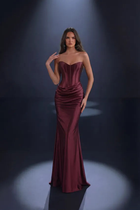 Woman wearing a mulberry color strapless gown against a dark background