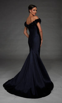 A woman modeling an off-the-shoulder mermaid gown in dark navy satin, photographed against a dark gray studio backdrop.