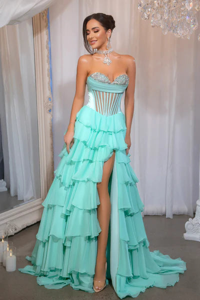 Model wearing Portia & Scarlett PS25961 gown featuring a strapless embellished bodice, sheer corset, high slit, and tiered ruffle skirt.