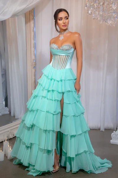 Model wearing Portia & Scarlett PS25961 gown featuring a strapless embellished bodice, sheer corset, high slit, and tiered ruffle skirt.