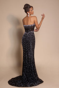 Woman wearing a black beaded evening gown against a beige background