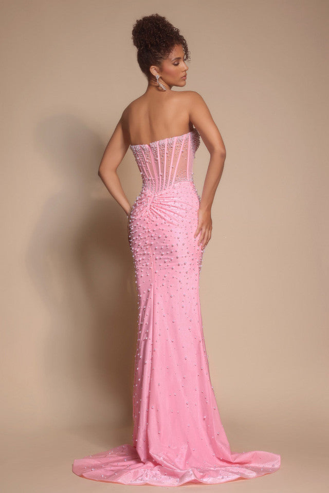 Woman wearing a pink strapless gown with intricate detailing on a beige background
