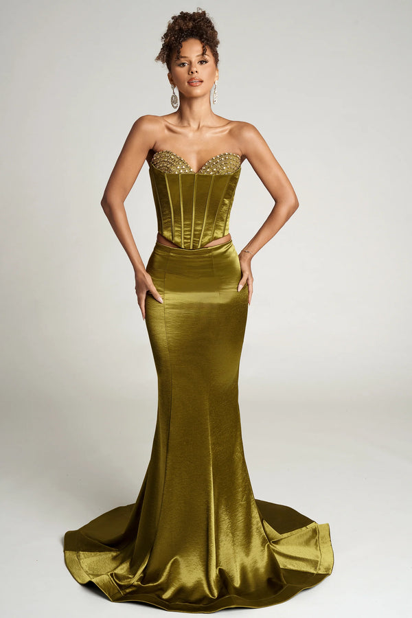 Woman wearing a strapless green evening gown with a fitted bodice and flowing skirt on a white background.