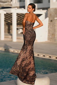 Woman in a strapless lace evening gown by a poolside.