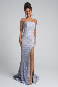 Woman wearing a strapless silver evening gown with a high slit on a gray background