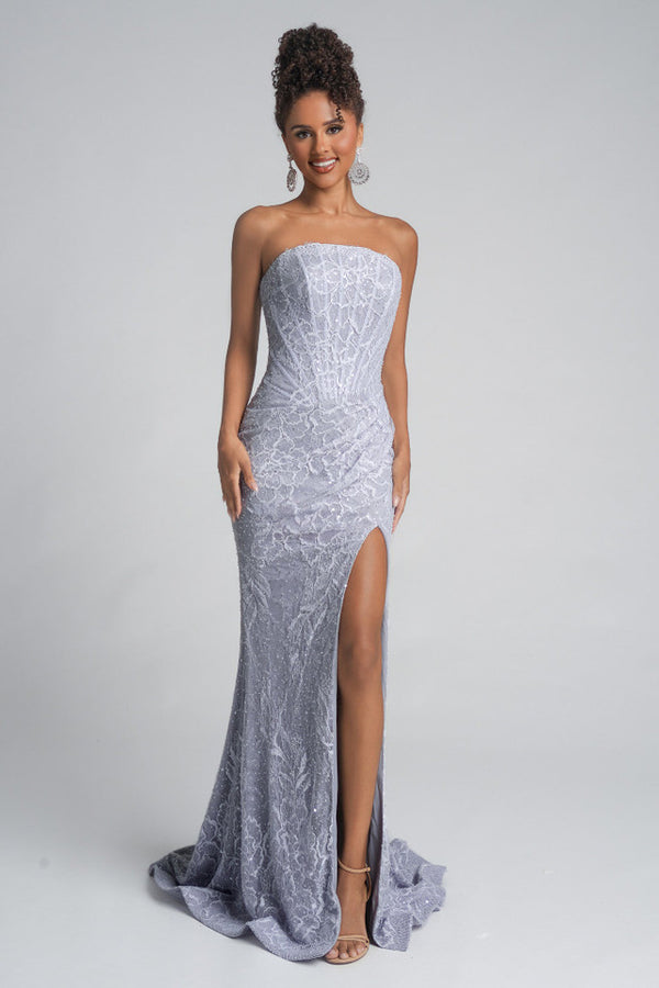 Woman wearing a strapless silver evening gown with a high slit on a gray background