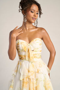 Woman wearing a strapless yellow and white floral dress against a plain background