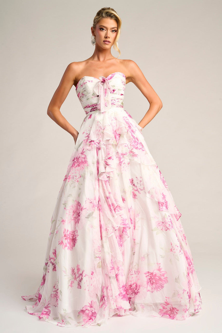 Woman wearing a strapless gown with pink floral pattern on a plain background