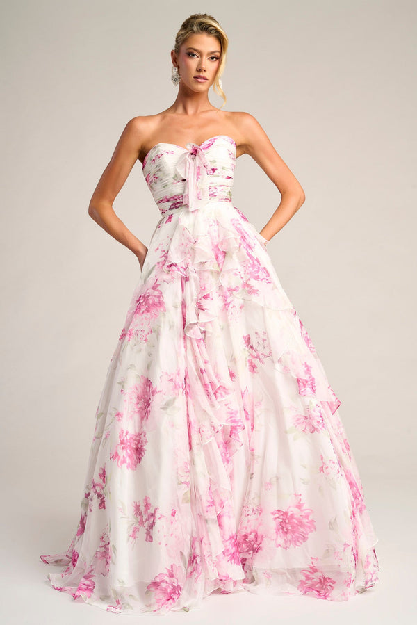 Woman wearing a strapless gown with pink floral pattern on a plain background