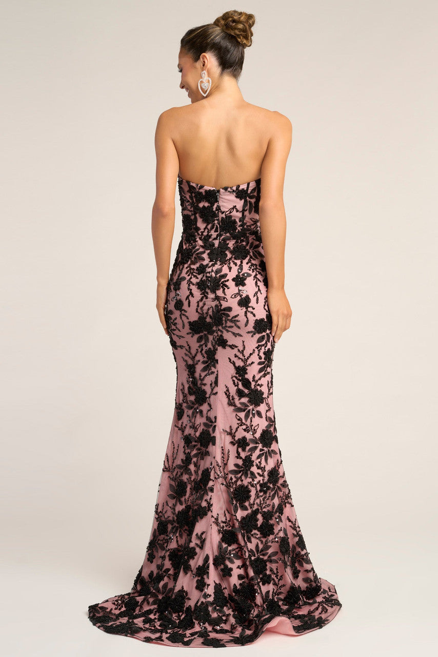 Woman wearing a strapless floral evening gown on a plain background