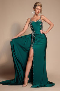 Woman wearing a green evening gown with a high slit on a beige background