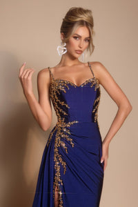 Woman wearing a blue evening gown with gold detailing on a beige background
