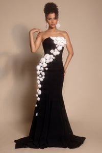 Black strapless gown with white floral embellishments on a beige background