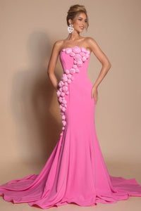 Woman wearing a pink strapless gown with floral embellishments on a beige background