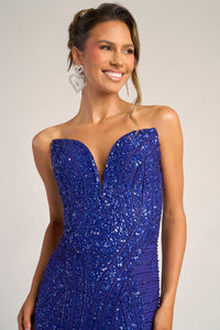 Woman wearing a cobalt blue sequin dress with a plain background