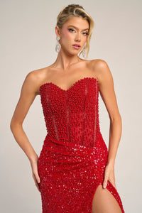 Woman wearing a red strapless dress with sequins on a neutral background