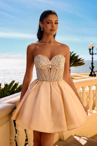 Woman in a strapless, embellished dress standing on a balcony with ocean view