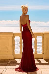 Woman in a red evening gown standing on a balcony with ocean view