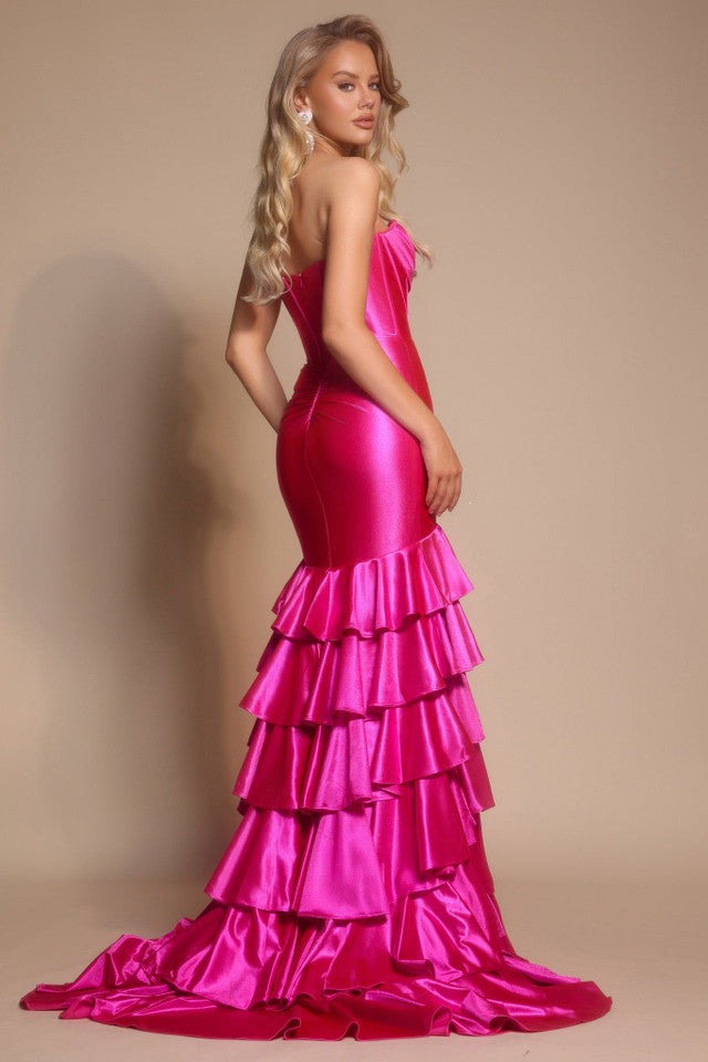 Woman wearing a fuchsia evening gown with ruffled layers on a beige background